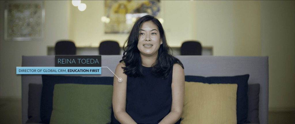 Screenshot of a video frame featuring Reina Toeda, Director of Global CRM at Education First, speaking on camera during a video interview. 